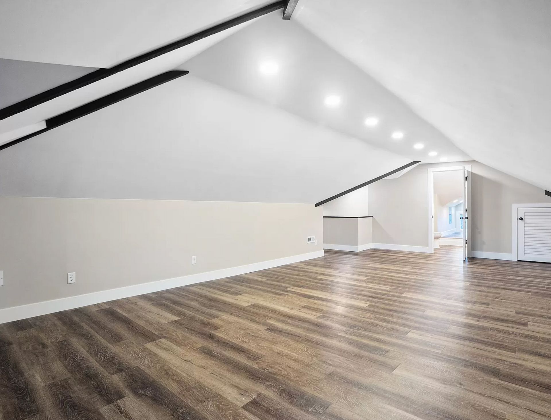 Cozy attic bonus room at Fenelon converted into a functional living space with exposed beams and soft lighting.