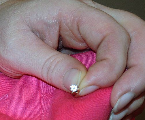 A woman is holding a diamond ring in her hand