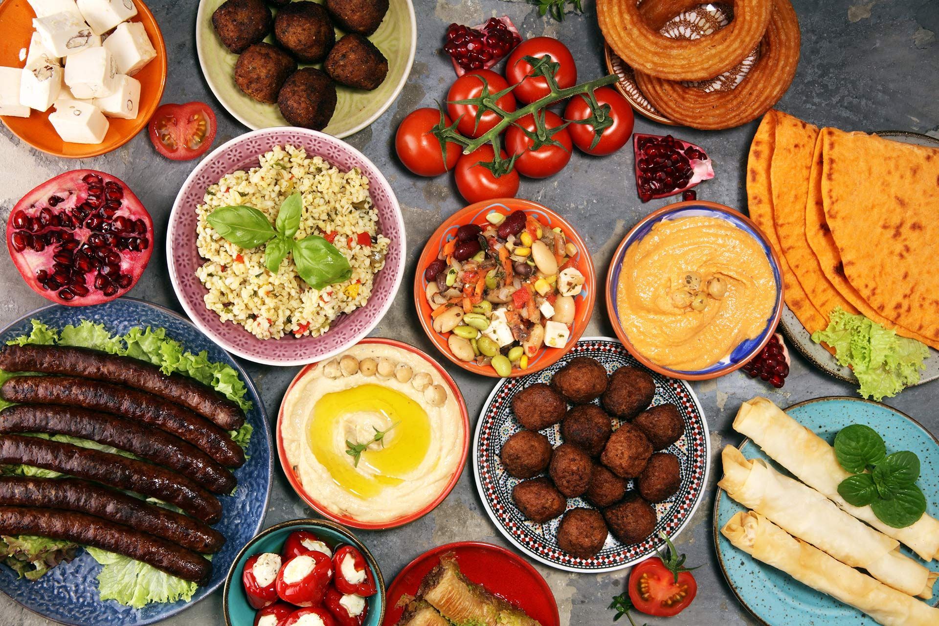 Colorful spread of assorted Mediterranean dishes on a table, including dips, breads, vegetables, and falafel.