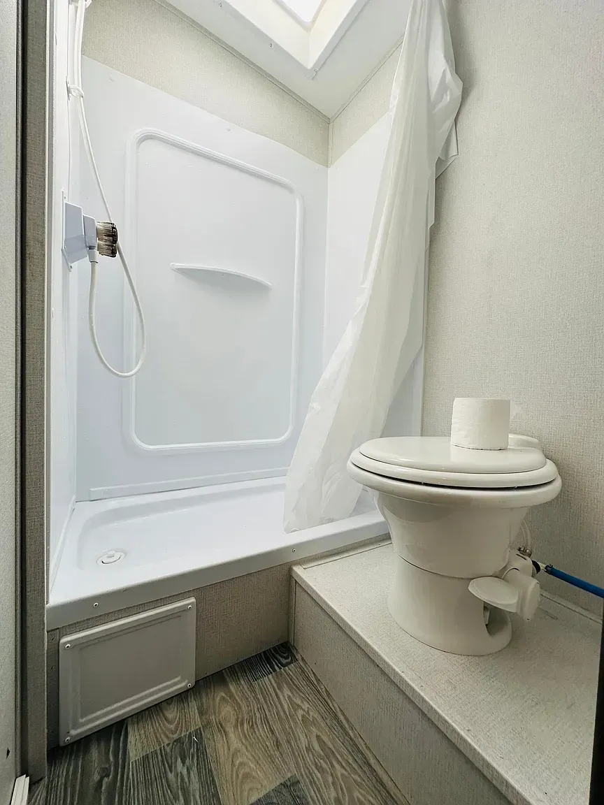 Small RV bathroom with a shower, toilet, and a skylight.