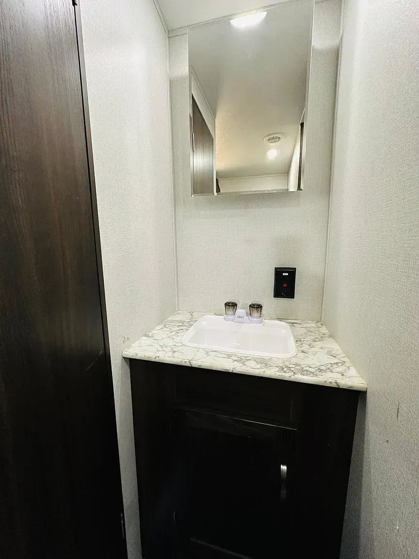 Bathroom with a white sink, dark cabinet, and mirror.