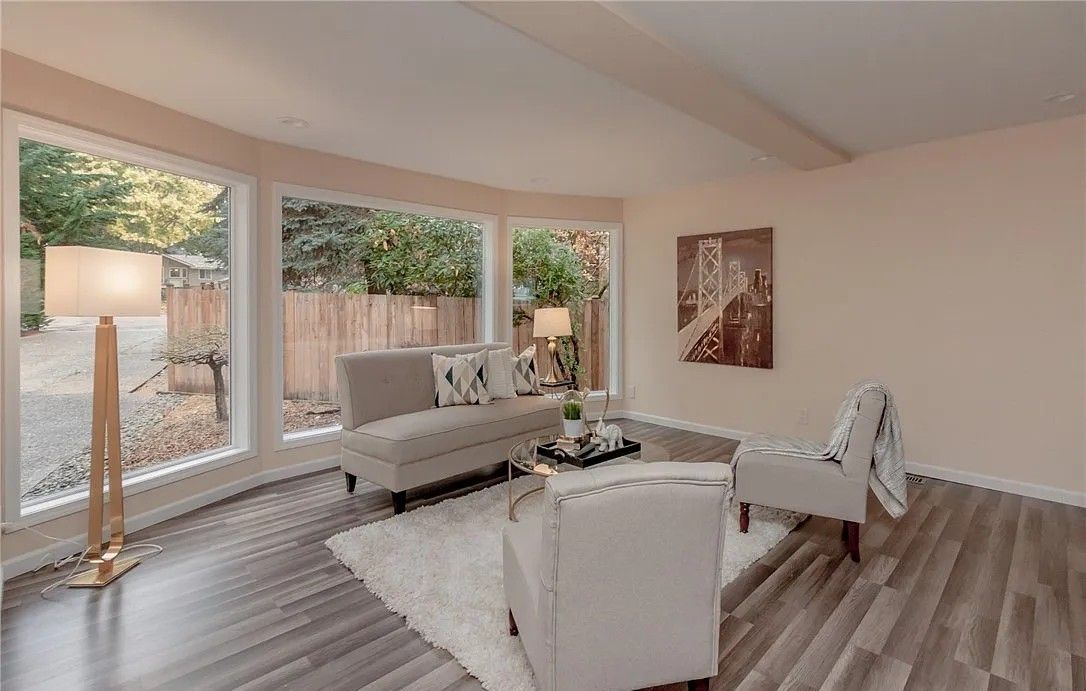 Living room with light gray walls, large windows, and modern furniture.
