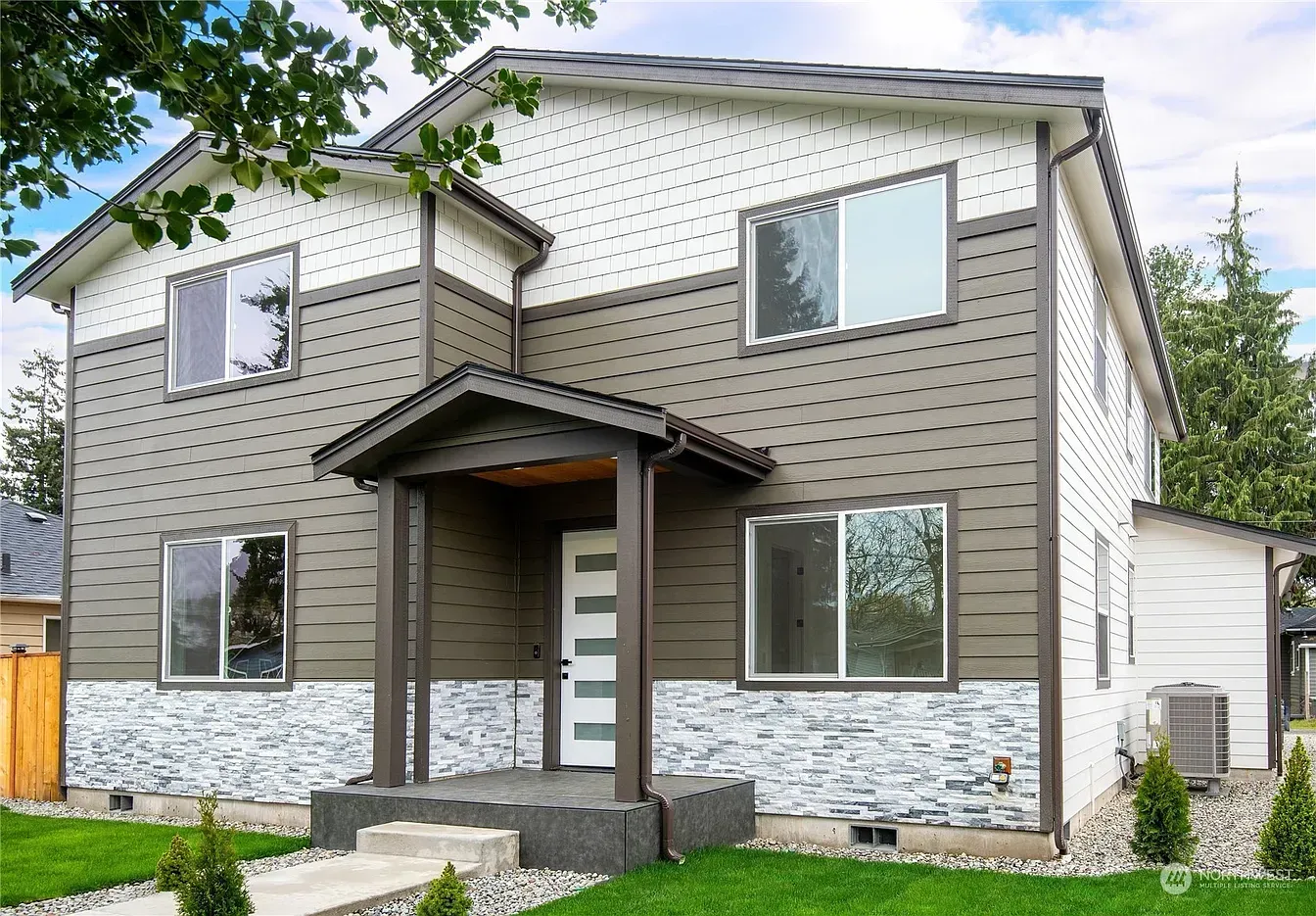 Two-story house with gray and white siding, stone accents, and a covered front porch.