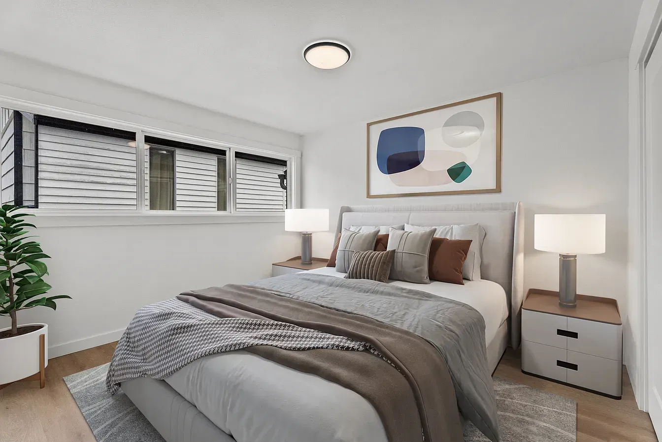 Bright modern bedroom with a gray bed, white nightstands, lamps, and abstract wall art