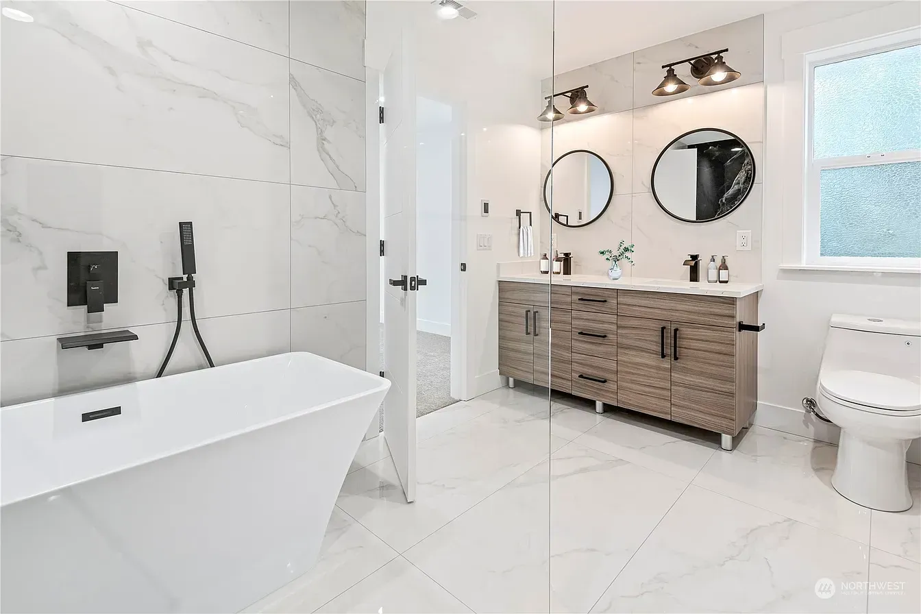 Modern bathroom with white tub, double vanity, and glass shower enclosure.