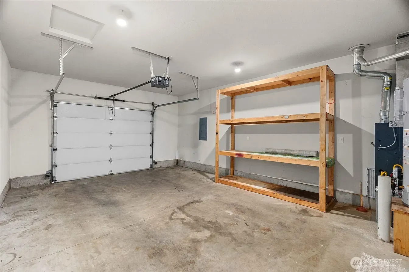 Empty garage with white door, concrete floor, and metal shelving unit on the right.