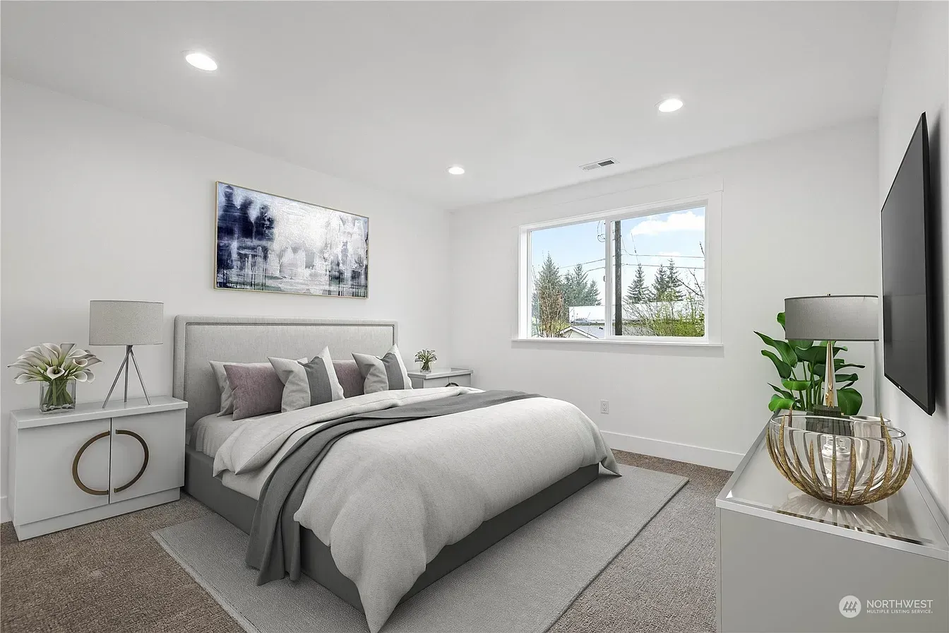 Bedroom with white walls, a bed, furniture, a window, and a mounted TV.