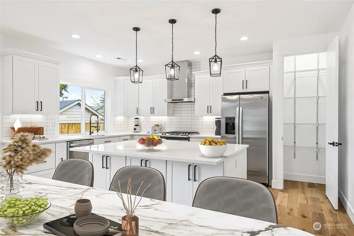 Bright, modern kitchen with white cabinets, stainless steel appliances, and a marble-topped island.