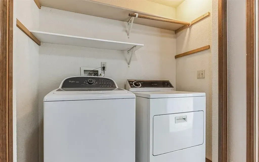 Laundry machines inside a closet with shelving. Washer and dryer are white.