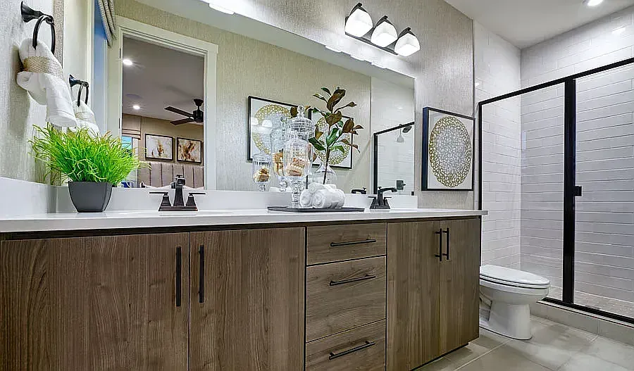 Bathroom with double vanity, wood cabinets, and frosted glass shower door.