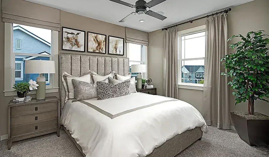 Bedroom with bed, nightstands, windows, art, and a large plant. Neutral colors.