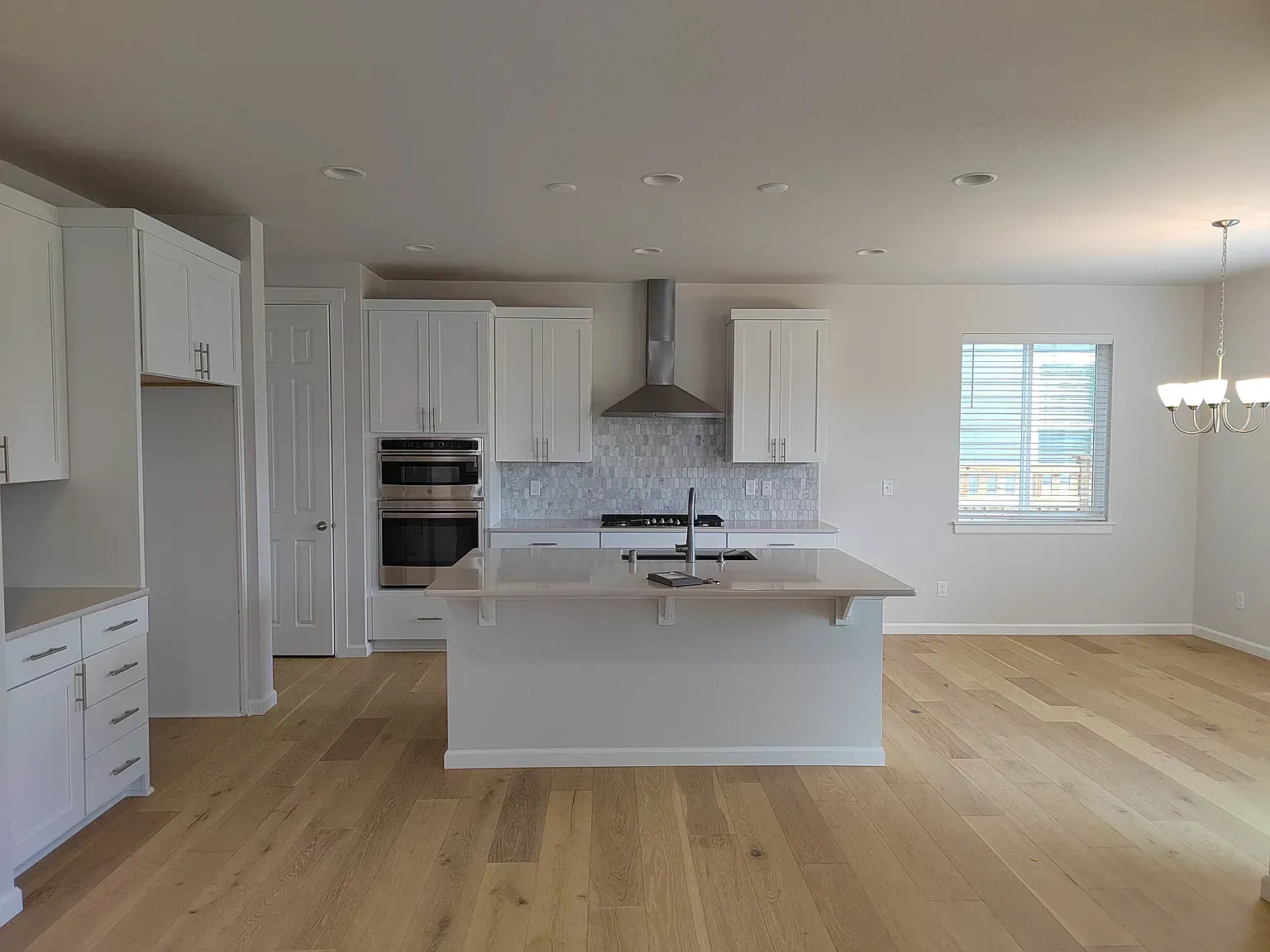 Bright, spacious kitchen with white cabinets, island, and wooden floors.