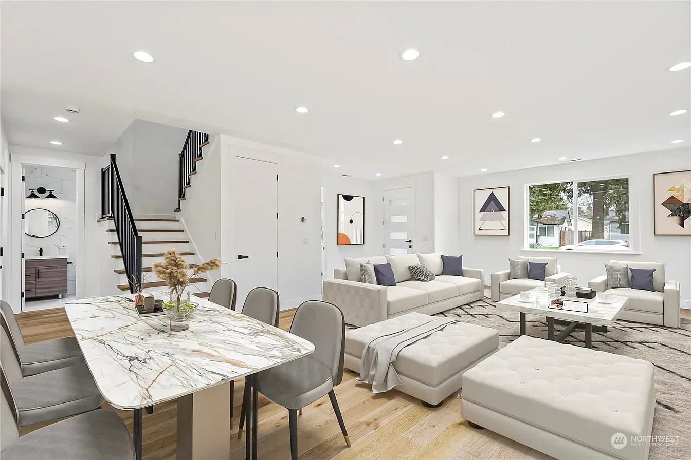 Bright open-plan living and dining area with modern furniture, light wood floors, and a staircase.