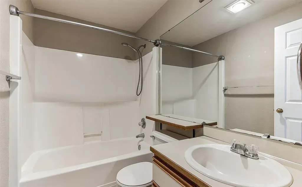 White bathroom with a tub, sink, and mirror.