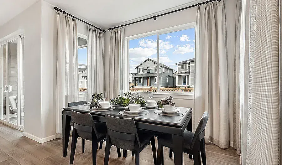 Dining room with black table, chairs, and window overlooking houses.