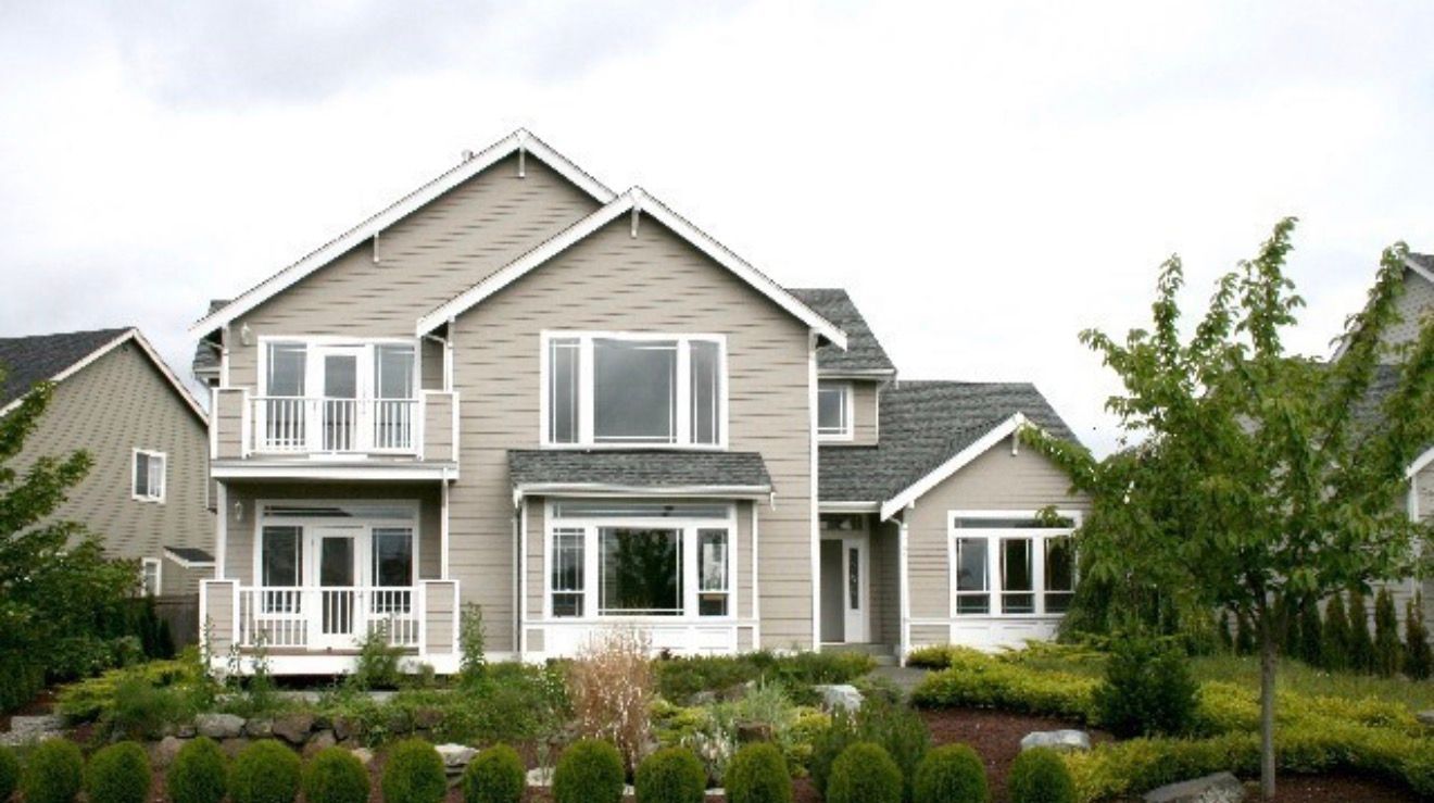 Gray two-story suburban house with white trim, front porch, and landscaped yard