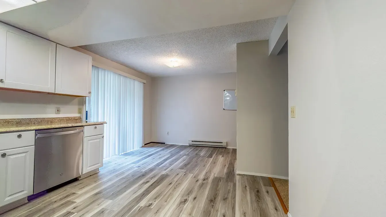 Kitchen and dining area with white cabinets, stainless steel appliances, and wood-look flooring.