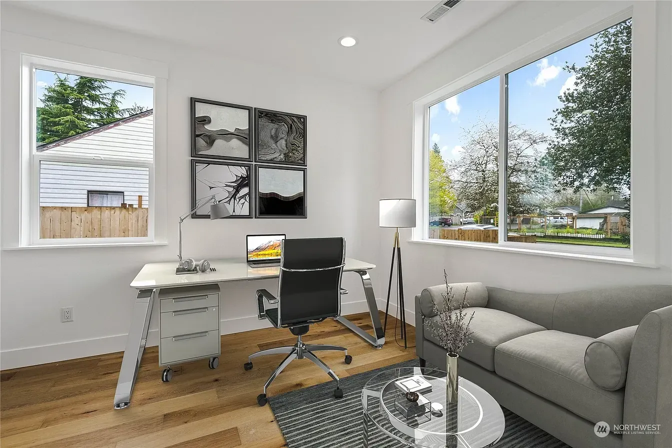 Home office with desk, couch, and large windows.  Artwork on wall above desk.