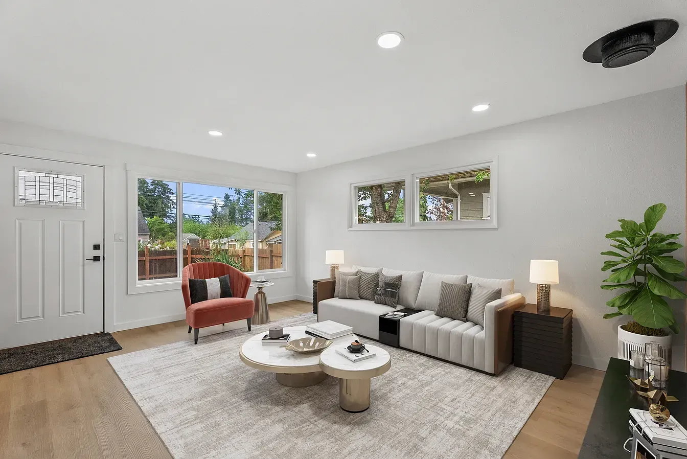 Bright modern living room with gray sofa, woven coffee table, armchair, and open patio doors