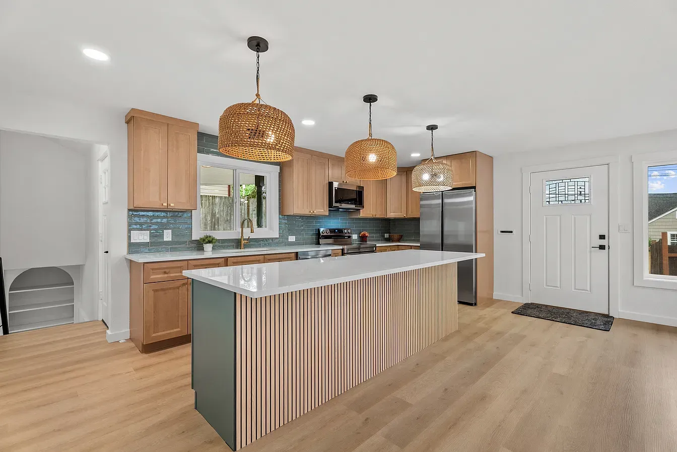 Bright modern kitchen with wood cabinets, marble island, woven pendant lights, and stainless steel appliances