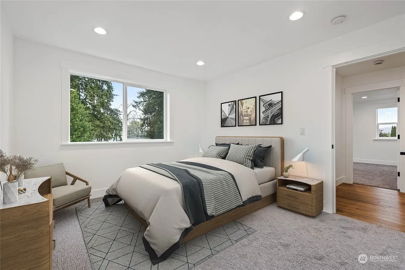 Bedroom with a bed, nightstand, dresser, and armchair. A window and art are also visible.