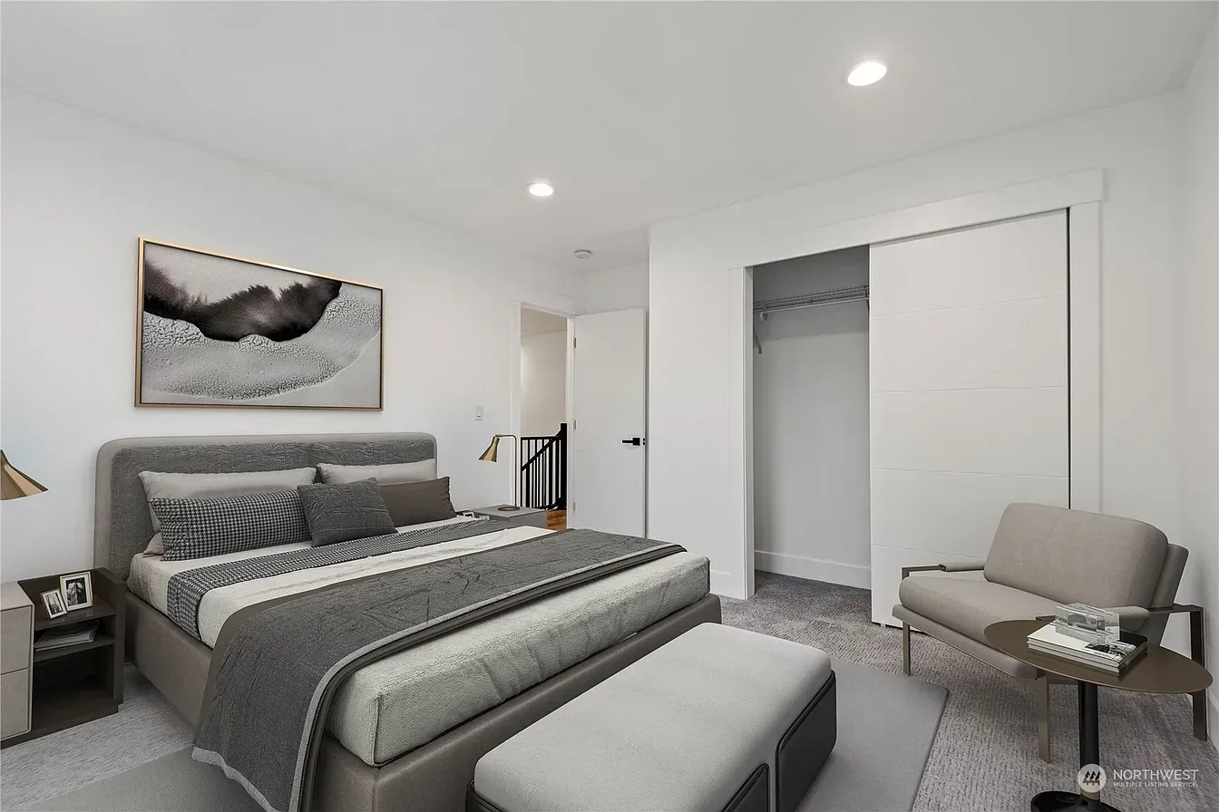Bedroom with gray bed, bench, chair, and art on a white wall.