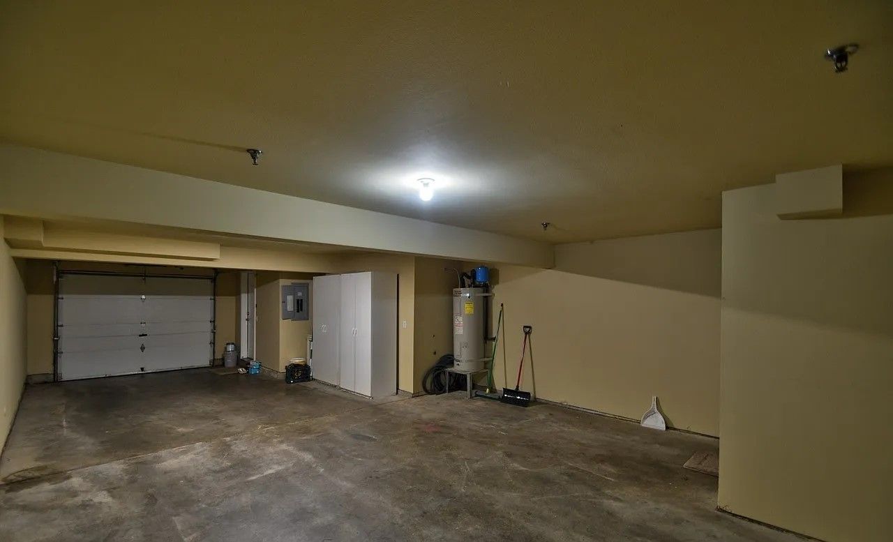 Empty garage interior with white garage door and concrete floor.