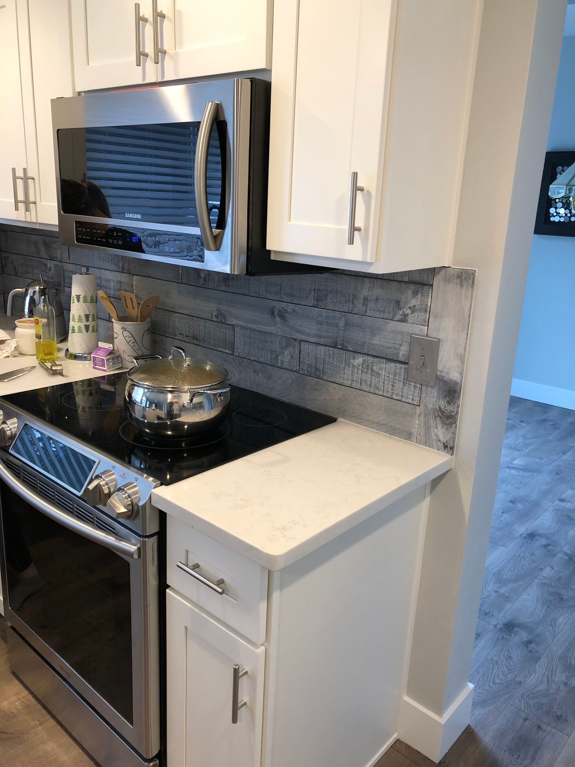 Kitchen with white cabinets, stainless steel appliances, and a gray backsplash.
