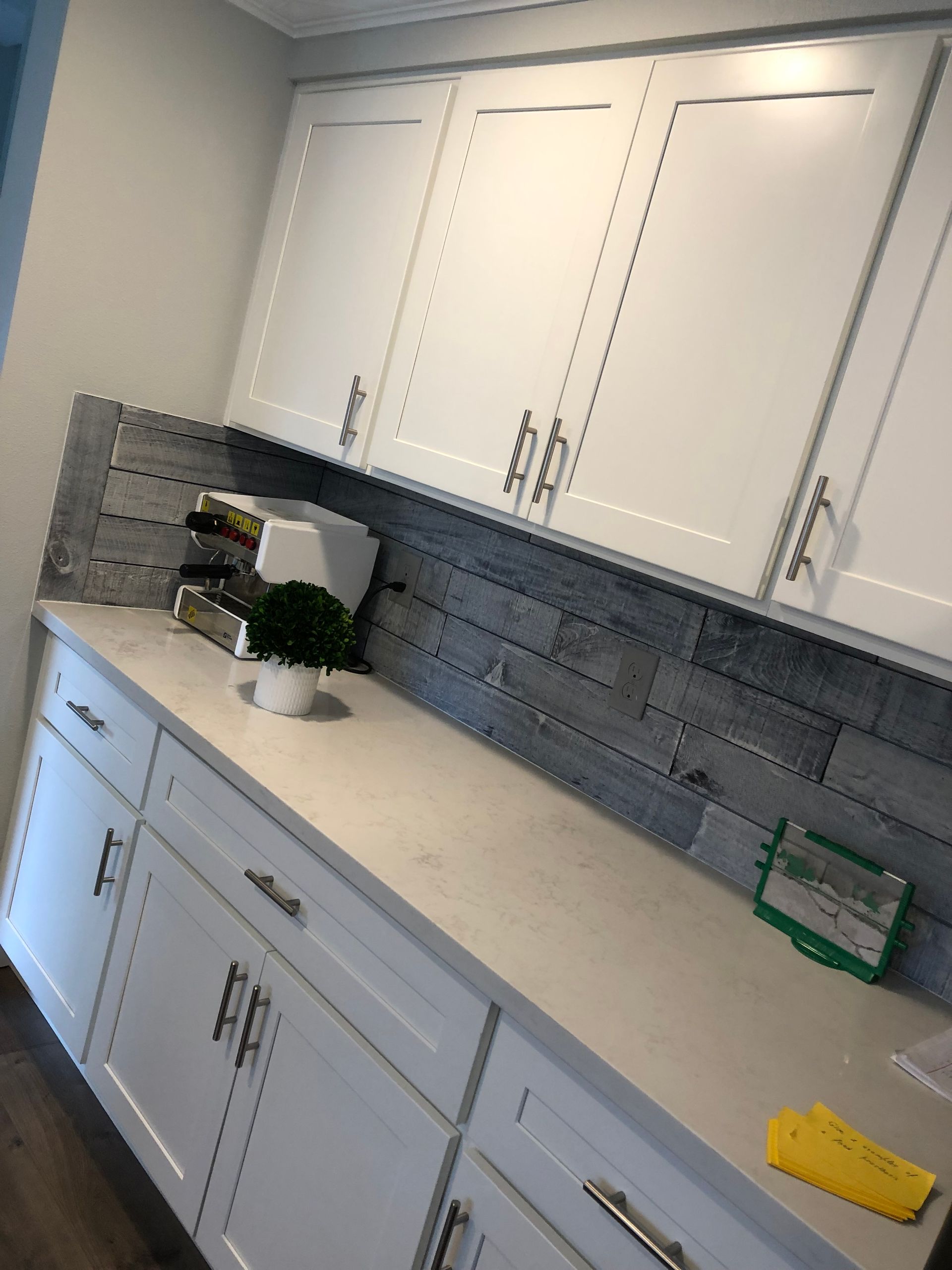 White cabinets above and below a countertop with a blue-gray backsplash.
