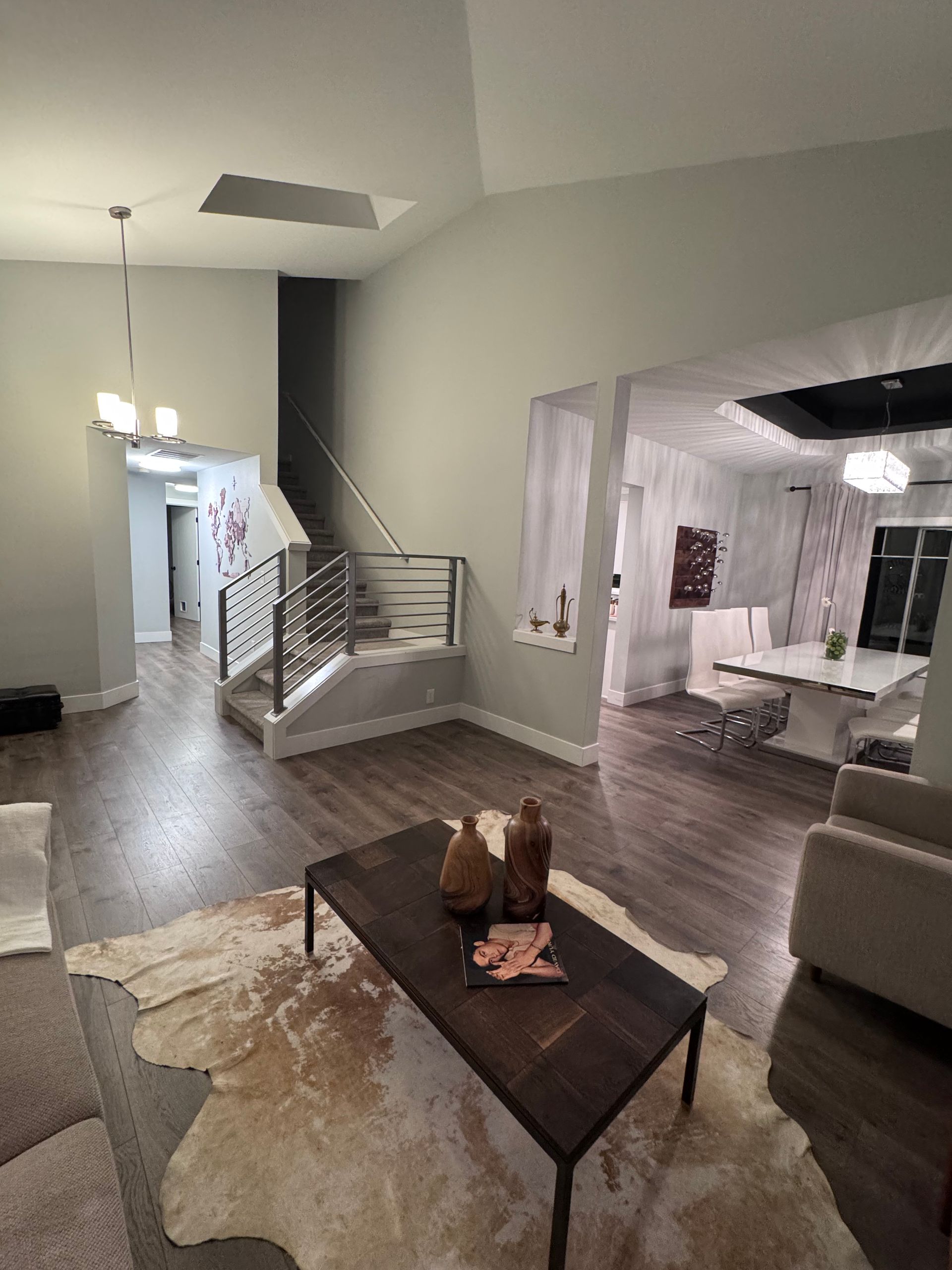 Living room with coffee table, staircase, and open doorway to dining area. Wooden floors.