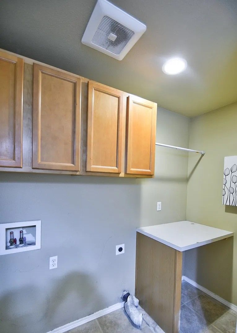 Laundry room with cabinets, folding counter, and ventilation fan.