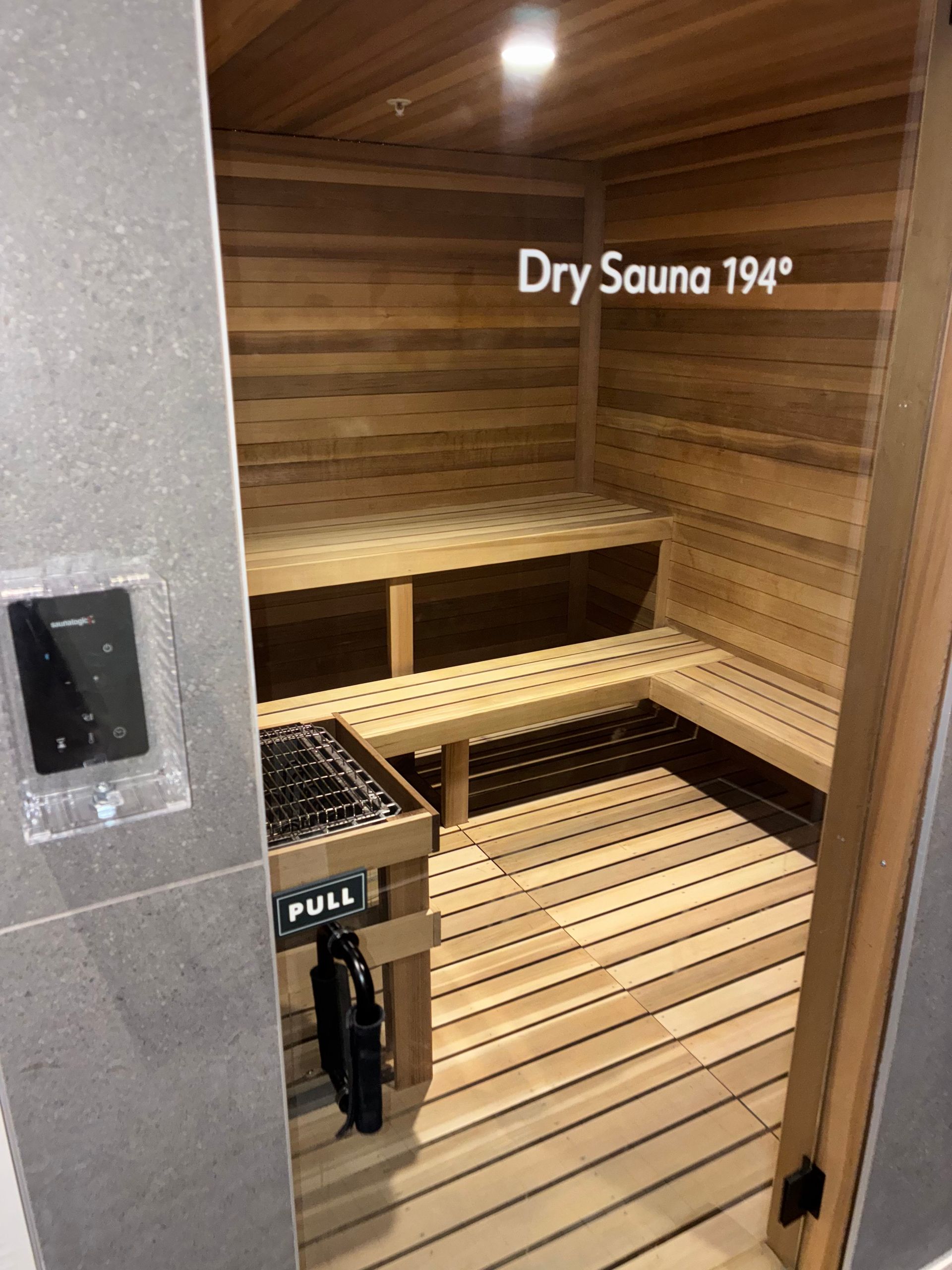 Dry sauna, wood-paneled, with benches, temperature displayed at 194 degrees. Control panel on left.