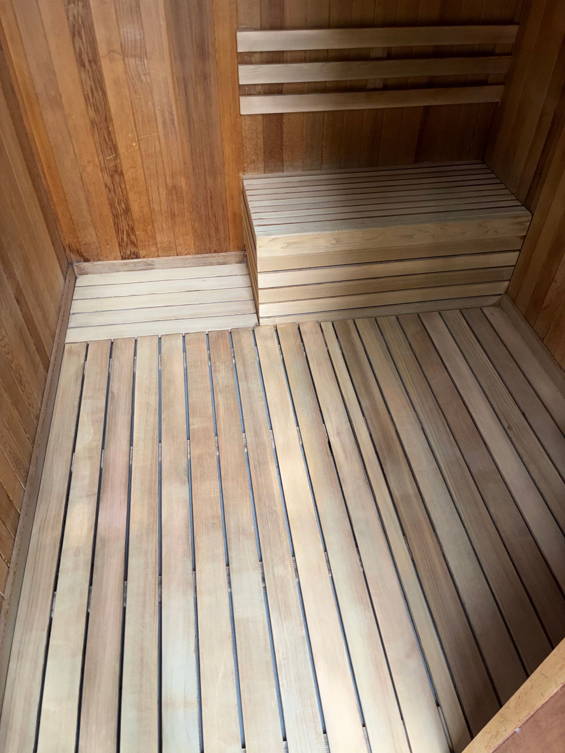Wooden sauna interior with slatted floor and bench. Cedar walls and ceiling.