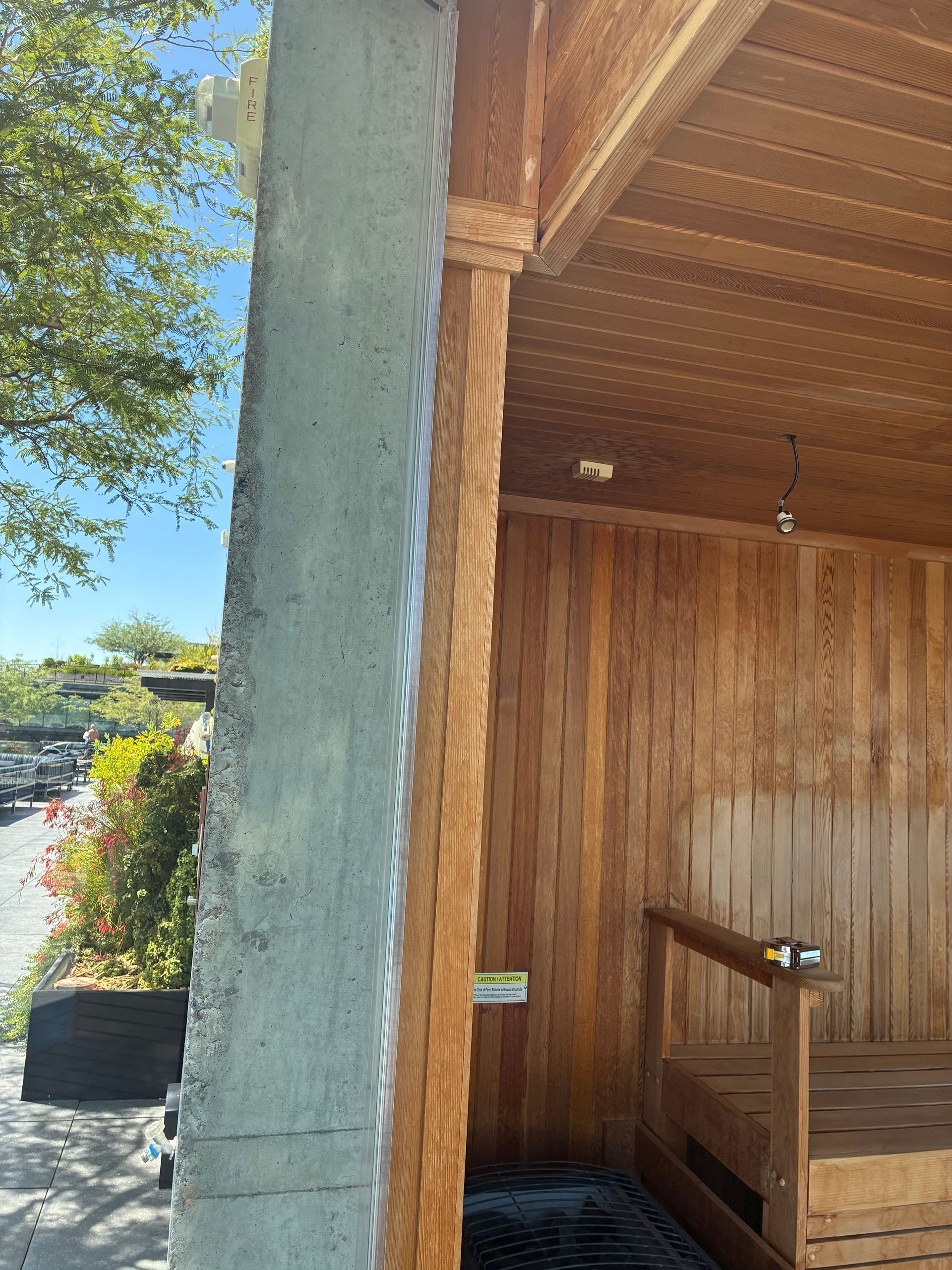 A concrete pillar next to a wooden sauna. The sauna has benches and wood panel walls.
