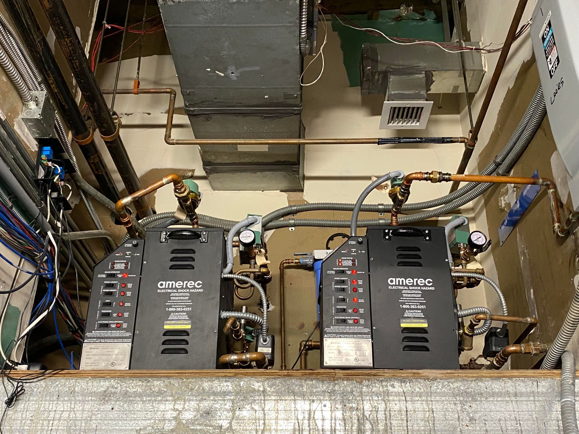 Two HVAC units with gauges and piping, installed in a utility space.