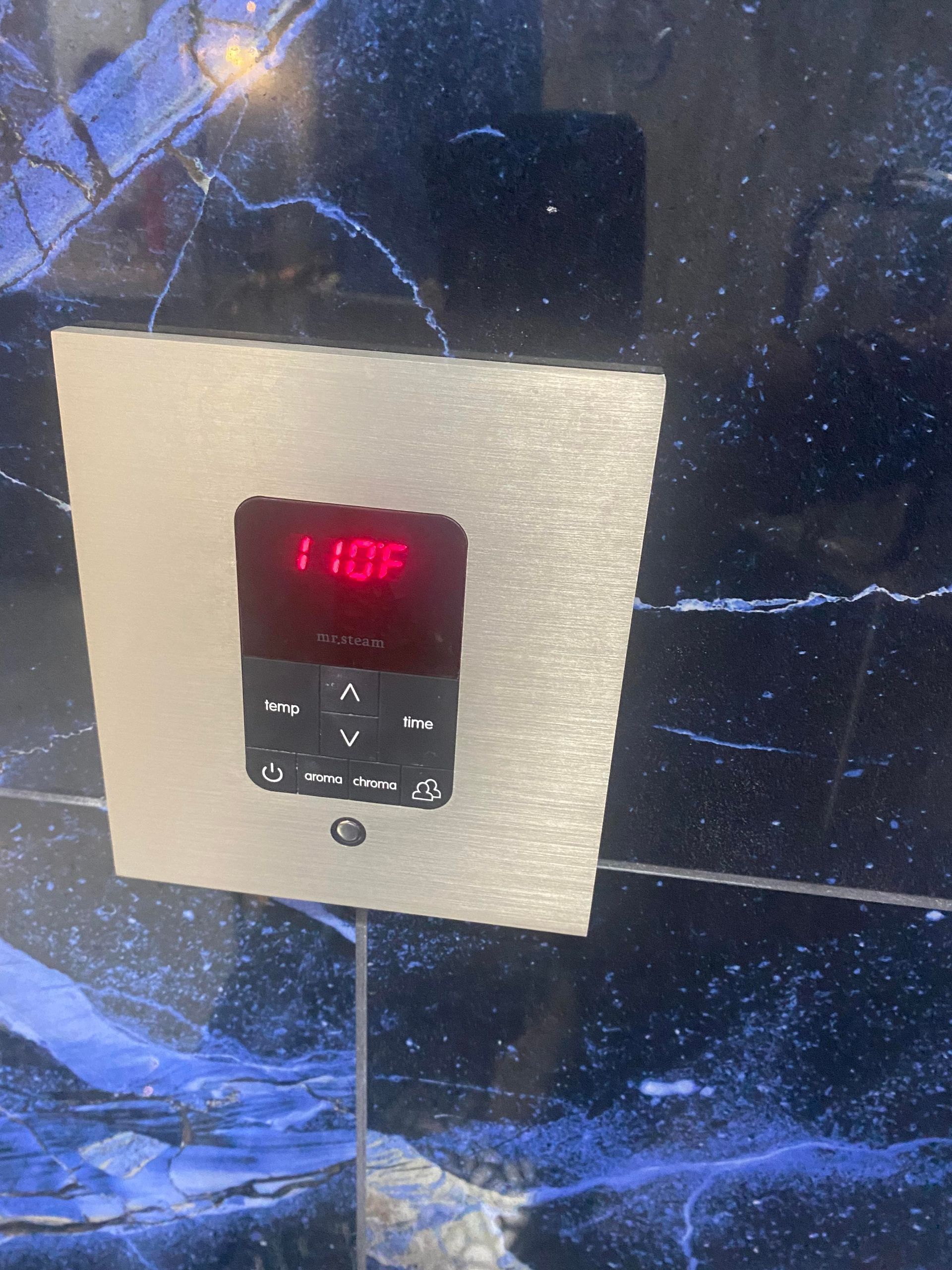 Elevator control panel with red display showing 110F. Silver plate on blue marble.