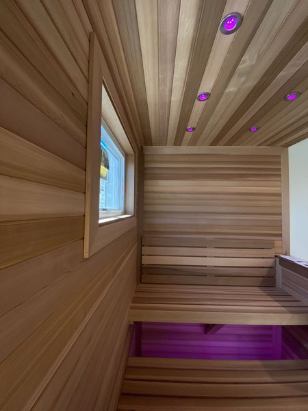 Wooden sauna interior with window and purple accent lighting.