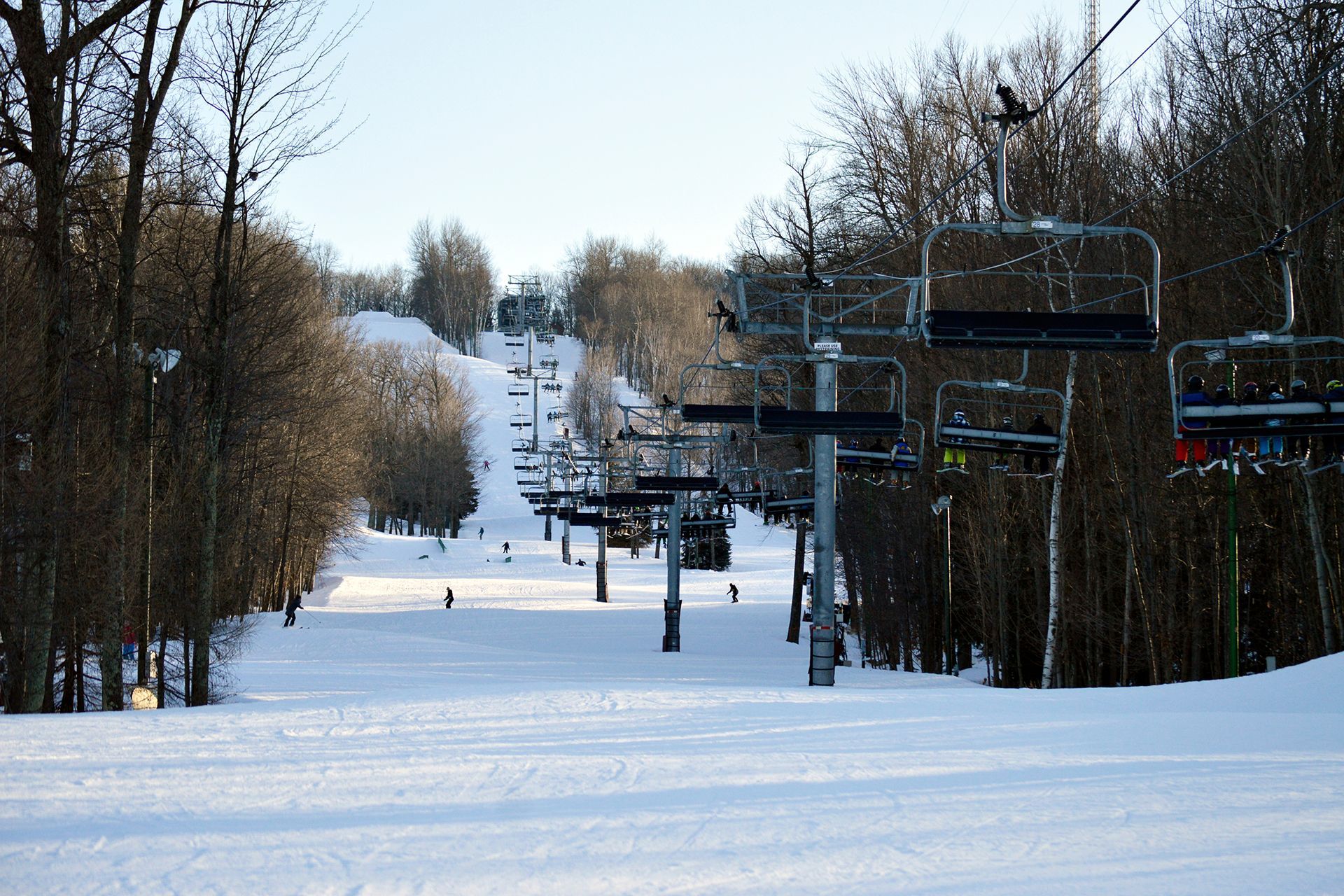 A ski lift going up a snow covered slope