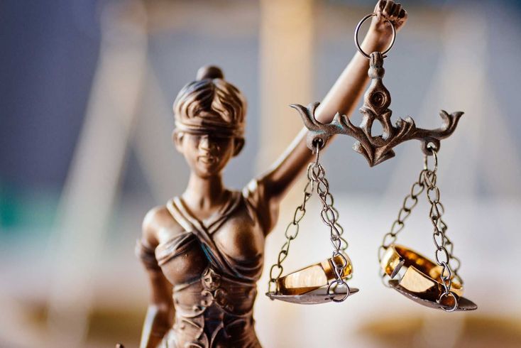 Bronze Lady Justice statue holding scales, with a judge’s gavel balancing on one side
