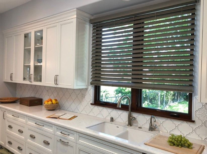 Taupe horizontal venetian blinds on a kitchen window above the sink