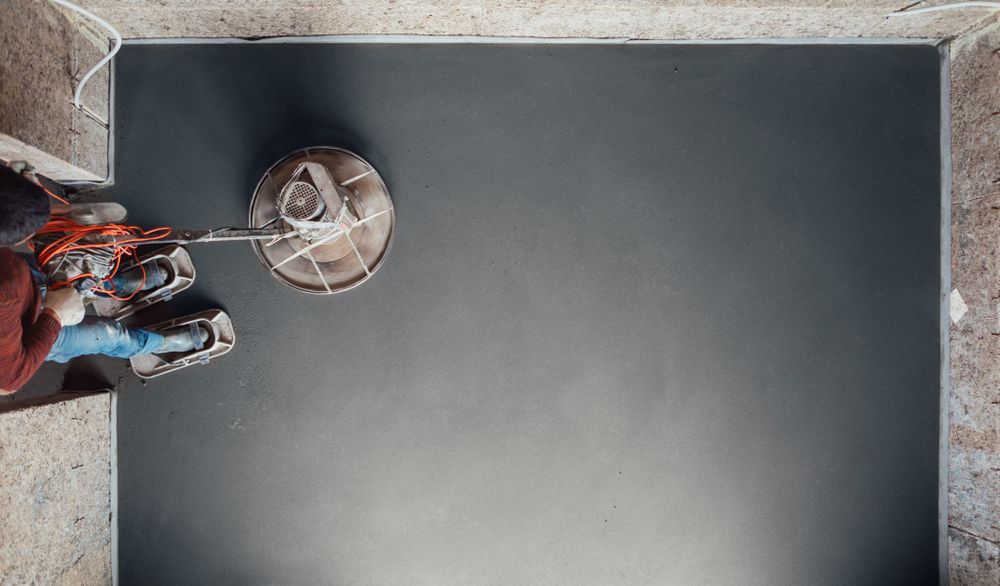 A Person Sanding a Dark Surface, Viewed From Above — Salisbury Concrete Contractors In Ocean Shores, NSW