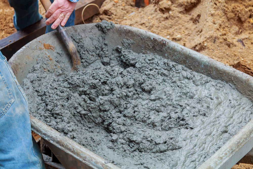 Wheelbarrow Filled With Wet Cement, Being Stirred With a Trowel — Salisbury Concrete Contractors In Tweed Heads, NSW