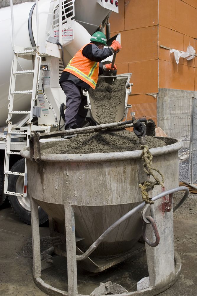 Worker in Safety Vest Transferring Concrete From Truck to a Large Bucket — Salisbury Concrete Contractors In Ballina, NSW