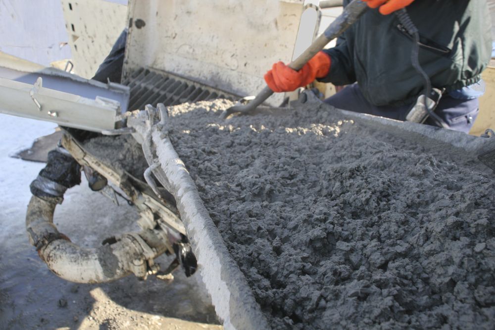 Person in Orange Gloves Shovels Concrete From a Truck Chute — Salisbury Concrete Contractors In Kingscliff, NSW