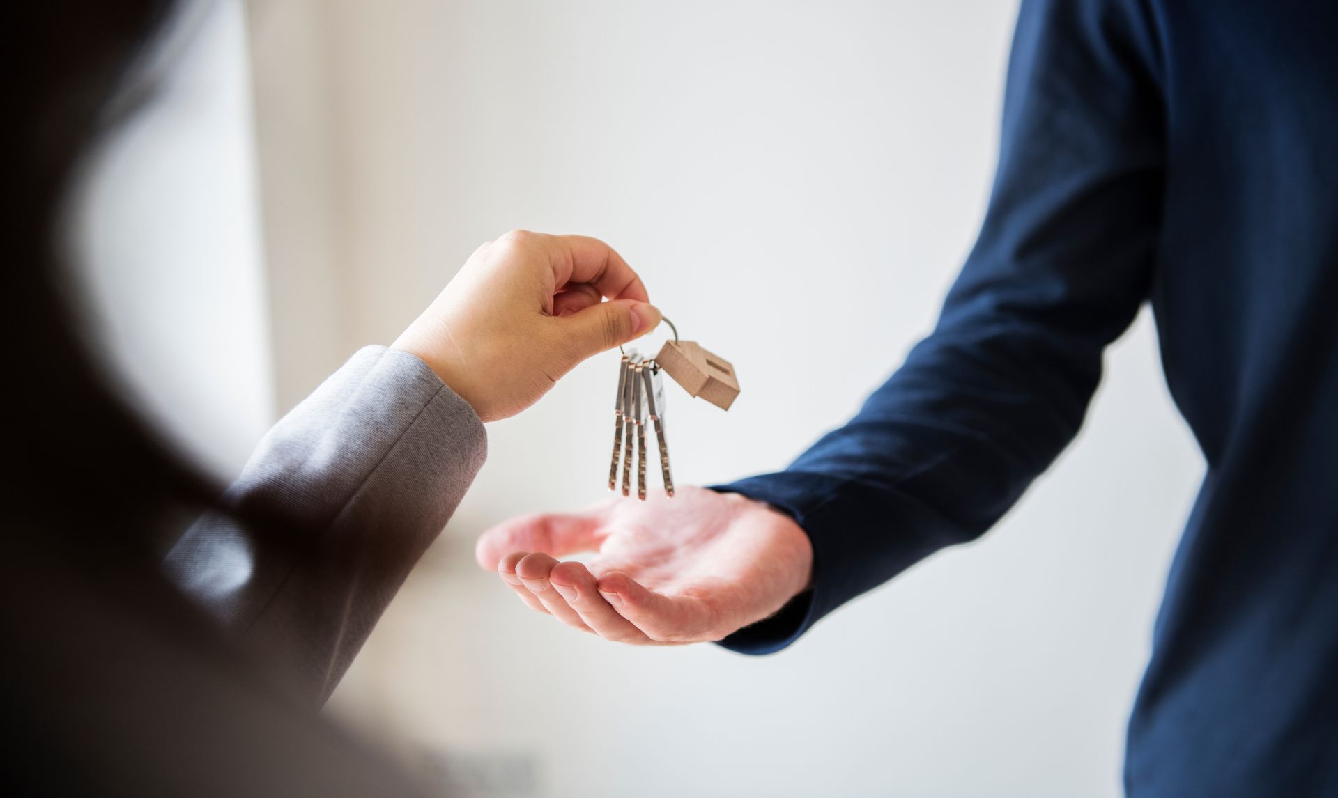 A woman is handing a man a bunch of keys.
