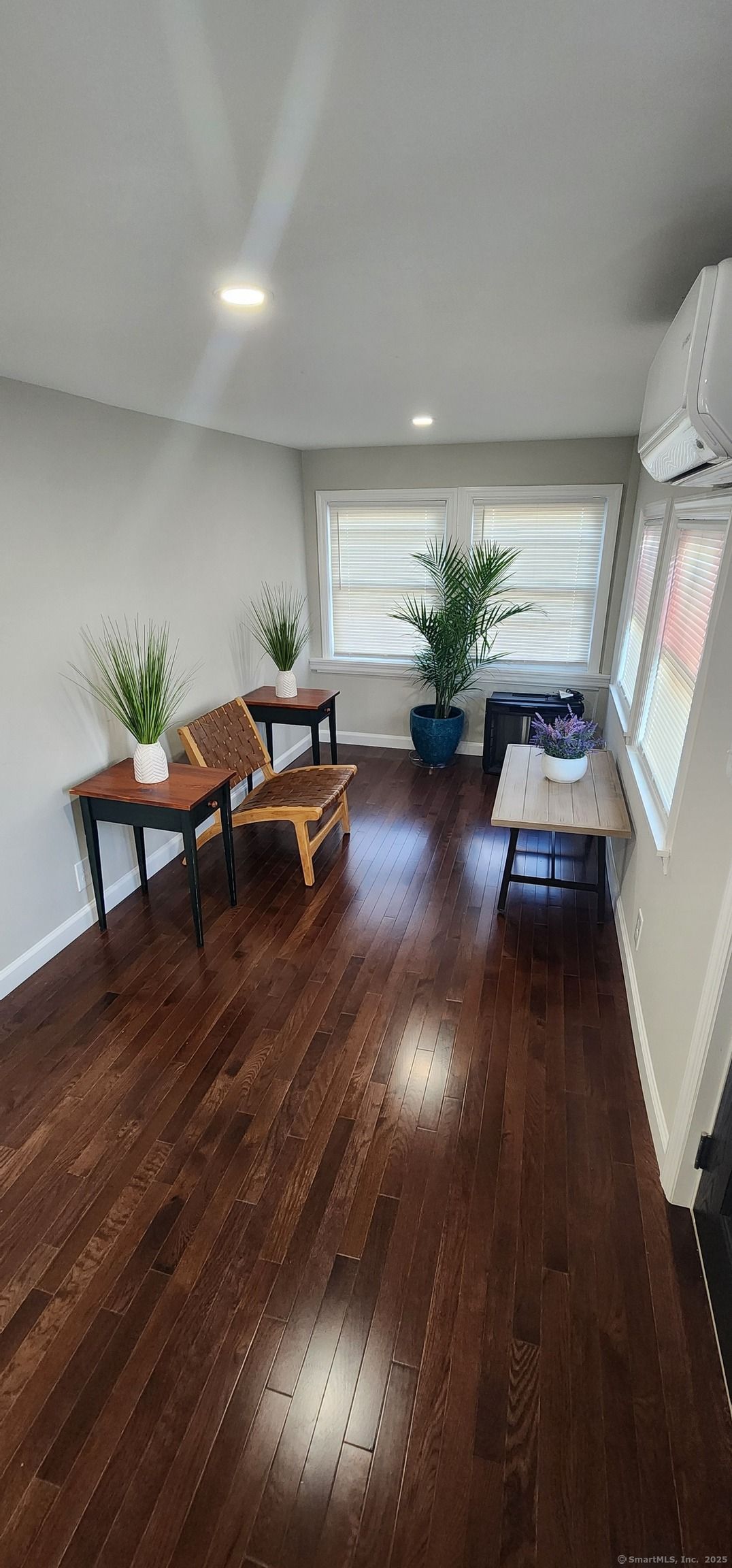A living room with hardwood floors , tables and chairs.