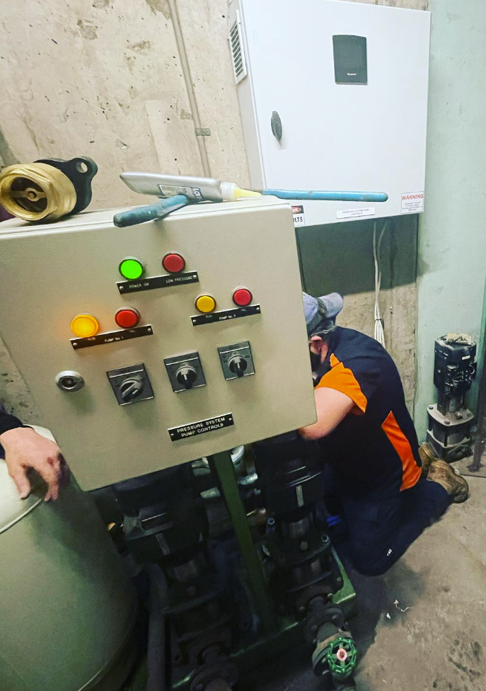 Pressure system pump control panel with technician working alongside