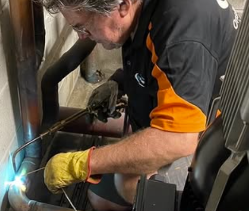 Licensed plumber soldering copper pipework on a pump system