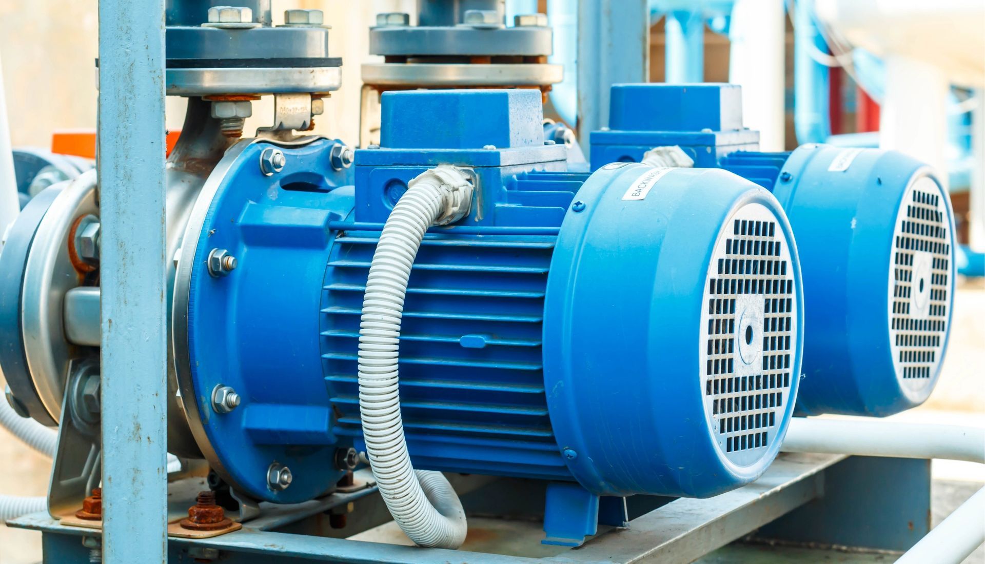 Blue industrial pumps connected to pipes, indoors.