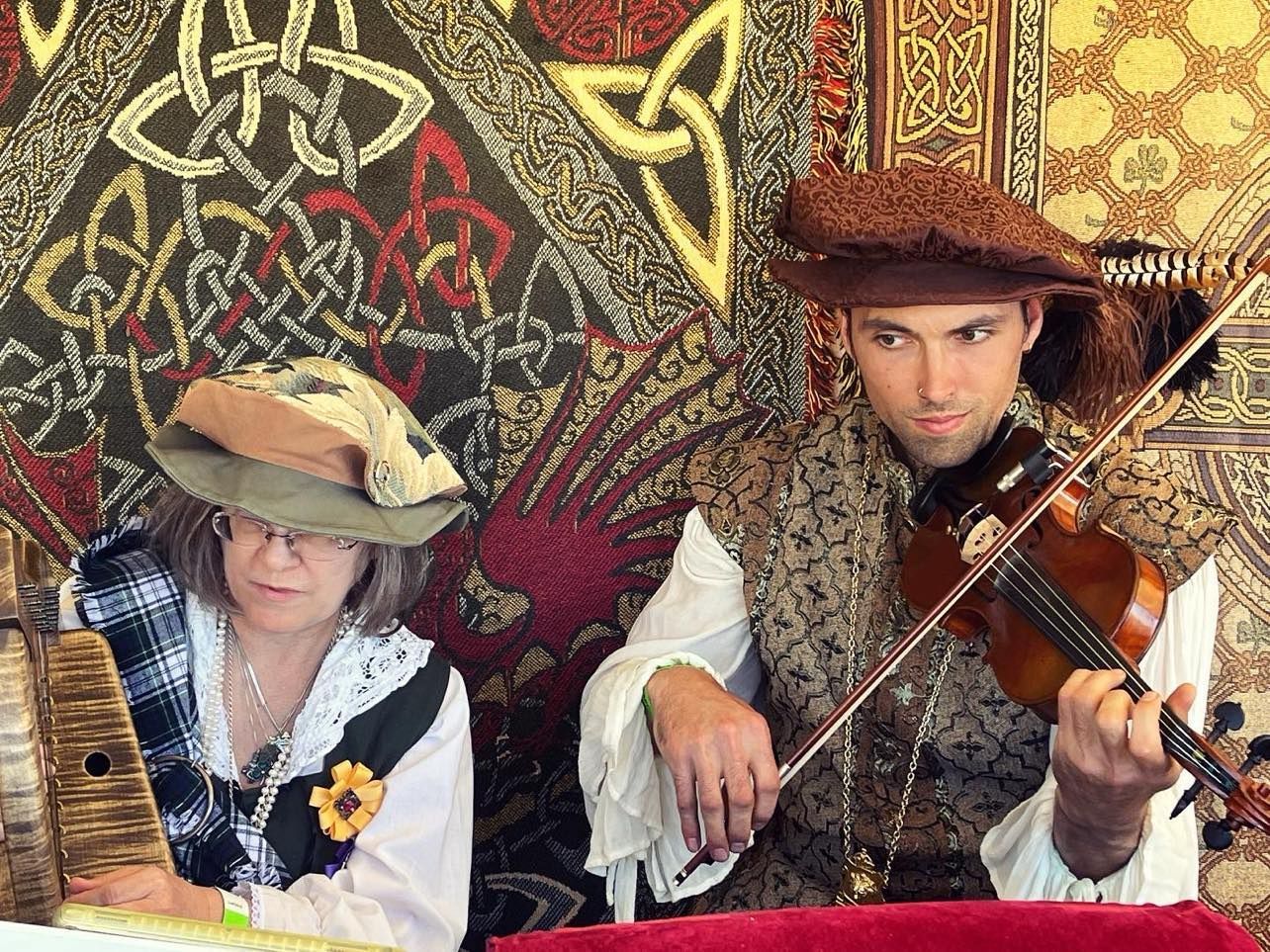 Two people in Renaissance attire play instruments at an event.